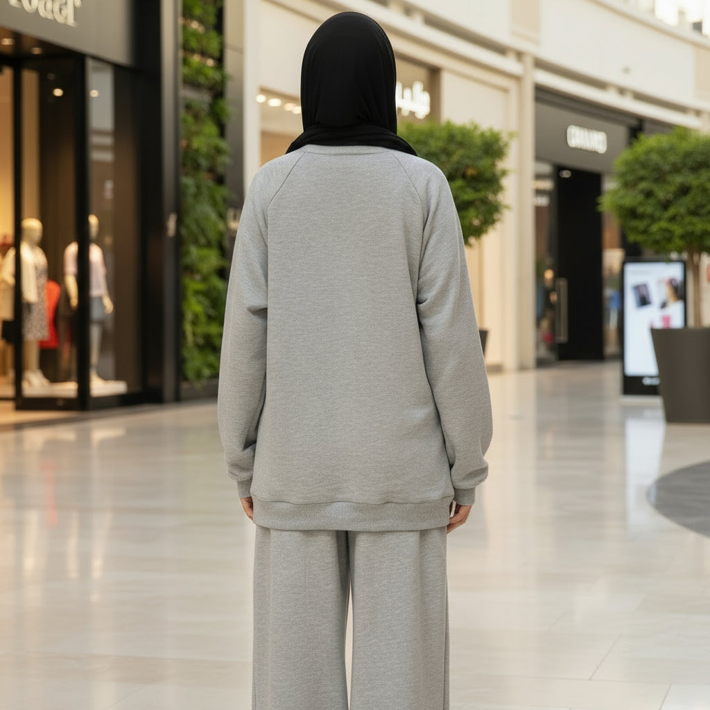 Person wearing a light gray outfit standing in a mall