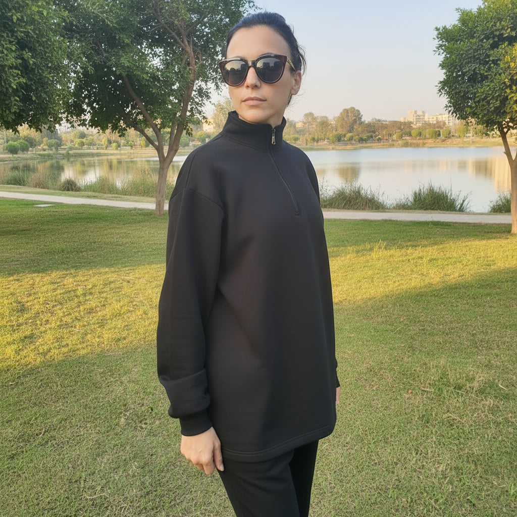 Person wearing a black outfit and sunglasses standing in lake park.