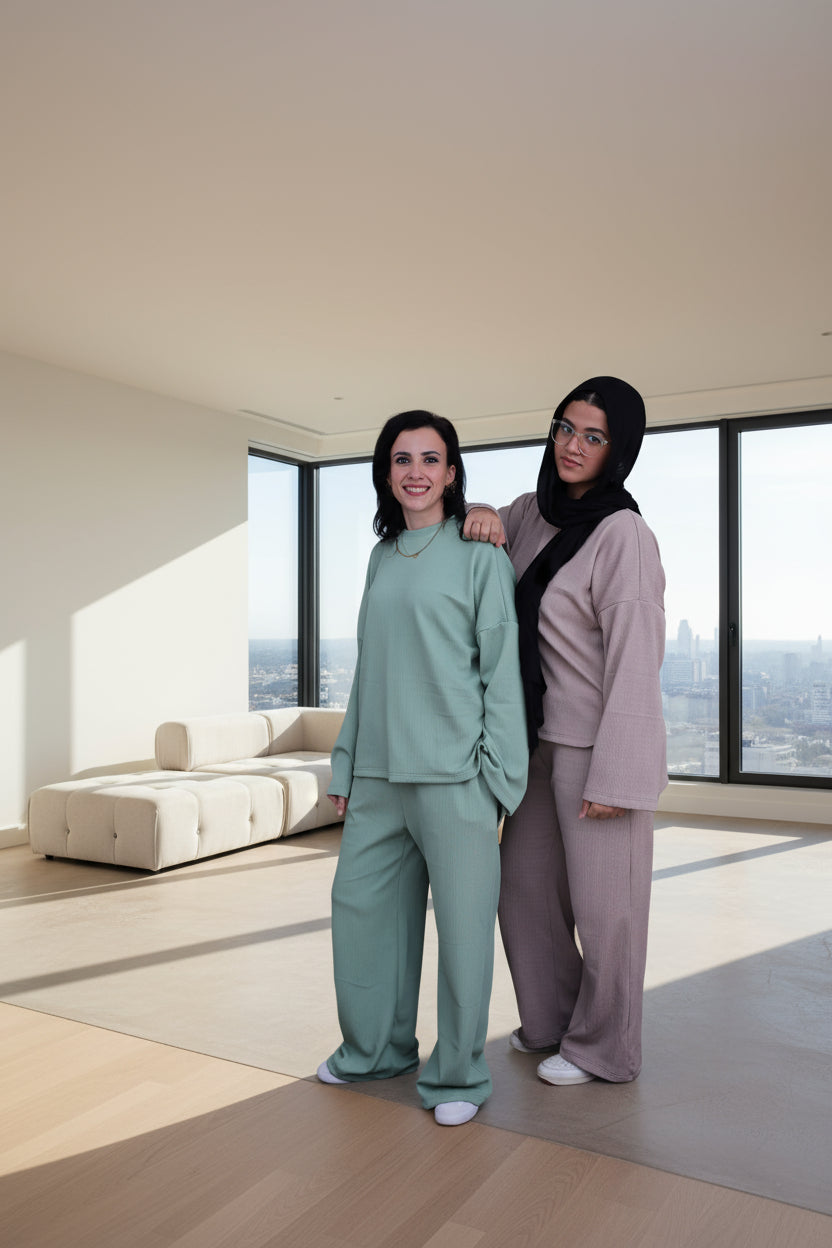 Two women wearing matching outfits against a black background