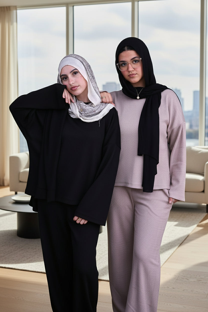 Two women wearing hijabs posing against a black background