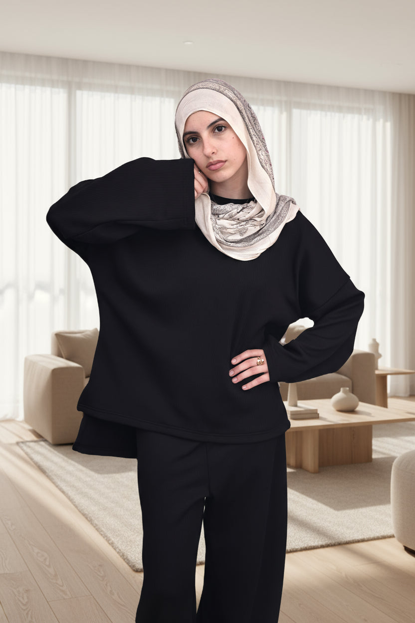 Woman wearing a black outfit with a beige headscarf on a white background