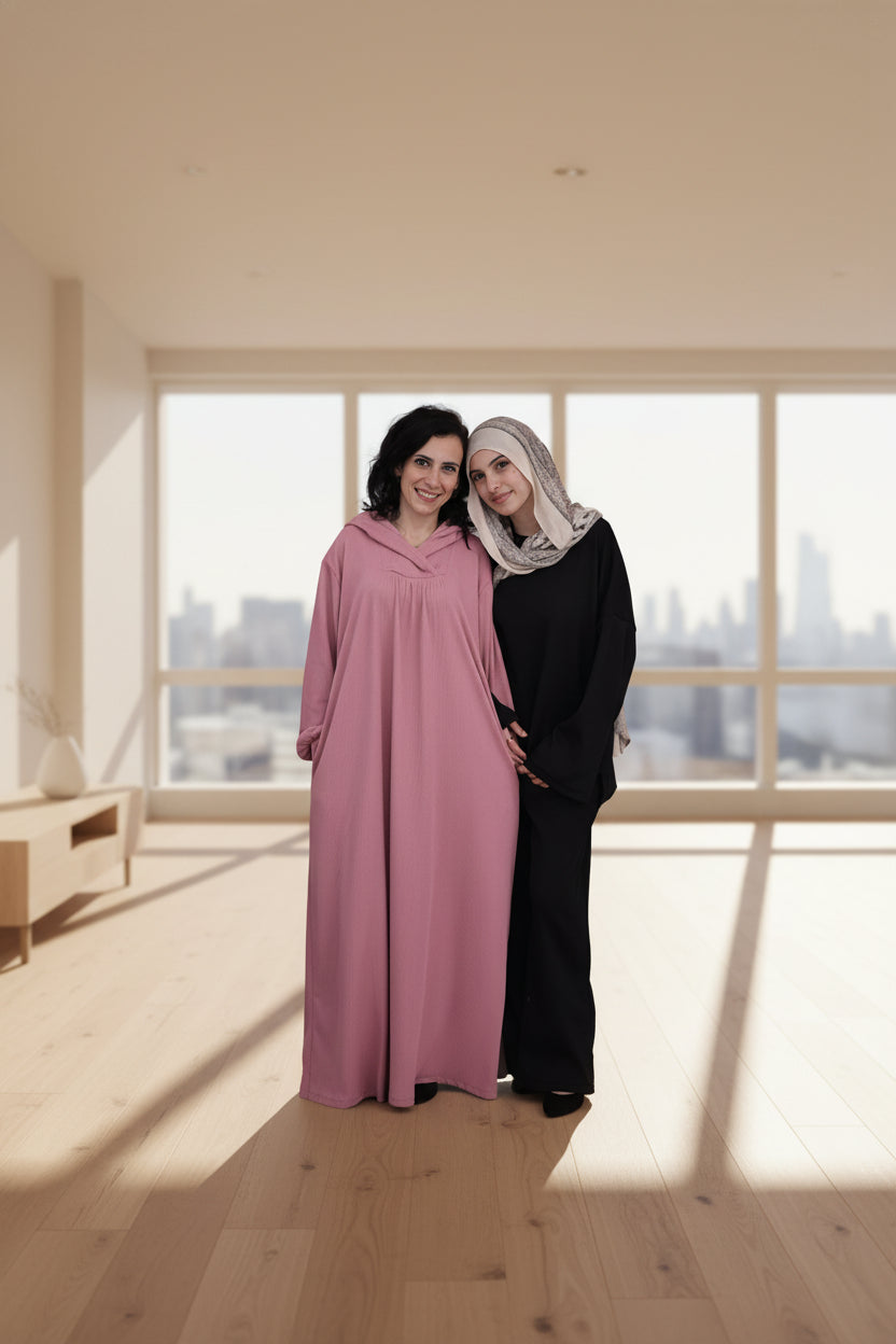 Two women standing together in a modern room with large windows showing a cityscape.